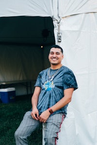 a man sitting on a chair in front of a tent